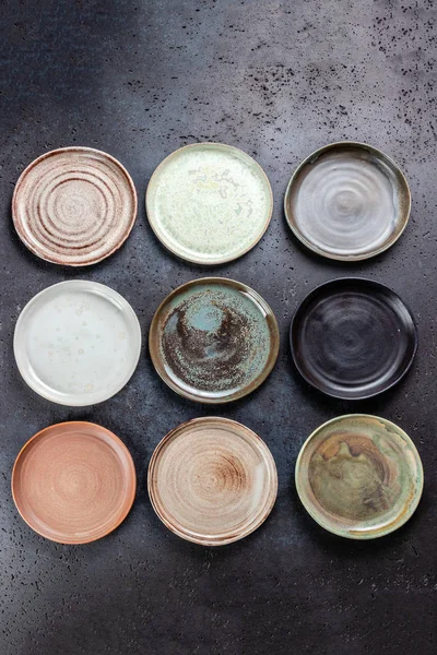 Абстрактный серый цементный фон с декоративной пустой круглый керамические блюда различных цветов, тарелки в керамической мастерской, ручной работы, вид сверху — стоковое фото