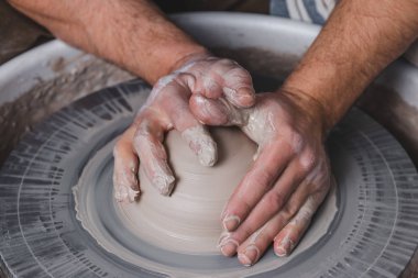 Potter, stüdyodaki çömlekçi çemberine yeni bir beyaz kil vazosu yapıyor. El işi, yaratıcılık ve sanat kavramı, yatay fotoğraf.