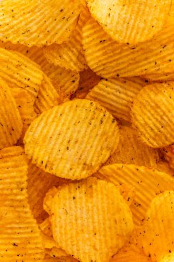 close-up view on corrugated golden chips background, grooved pattern and texture of fast food with copy space