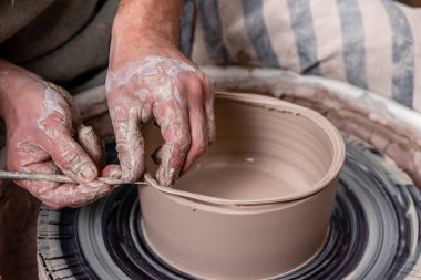 Potter, stüdyodaki çömlekçi çemberinde bir kase beyaz kil yapıyor. Yaratıcılık ve sanat kavramı, yatay fotoğraf.