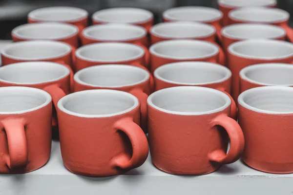 Mug merah keramik yang ditumpuk, produk buatan tangan dari tanah liat setelah dipanggang dalam tungku di studio tembikar — Stok Foto