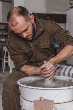 Potter, stüdyoda çömlekçi çemberinde bir kavanoz beyaz kil yapıyor. Yaratıcılık ve sanat kavramı, dikey fotoğraf.