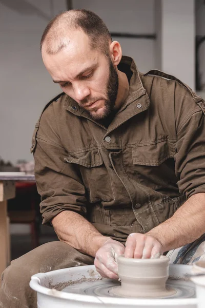 Potter, stüdyoda çömlekçi çemberinde bir kavanoz beyaz kil yapıyor. Yaratıcılık ve sanat kavramı, dikey fotoğraf.