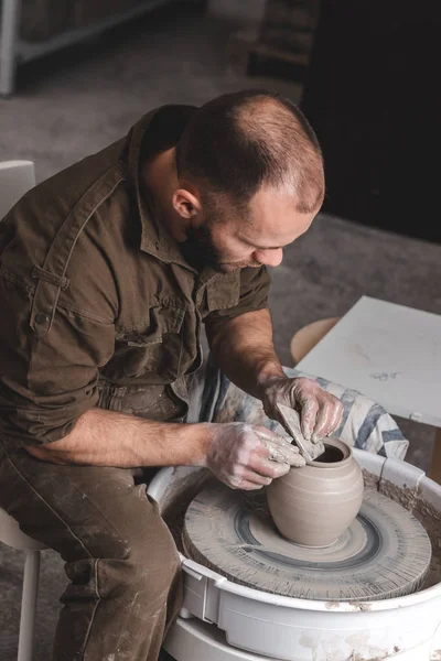 Pottenbakker maakt een schaal van witte klei op de pottenbakkerswiel cirkel in studio, concept van creativiteit en kunst, verticale foto, bovenaanzicht — Stockfoto