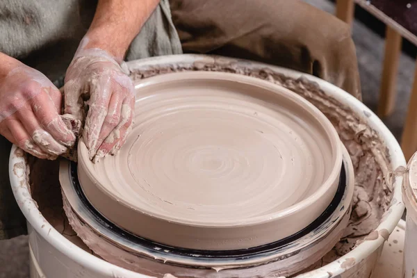 Potter fare una grande ciotola piatta di argilla bianca sul cerchio ruota del vasaio in studio, concetto di creatività e arte, foto orizzontale — Foto Stock