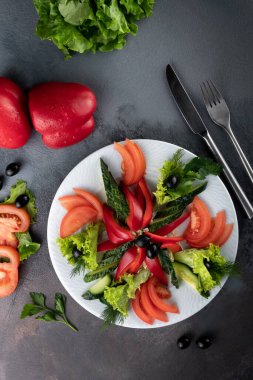 Domates, dolmalık biber, salatalık dilimleri, beyaz tabakta marul ve kekik, kırsal alanda fotokopi alanı ile gri çimento arka planda servis edilir, yemek restoranında dilimlenmiş çiğ sebzeler, üst manzara