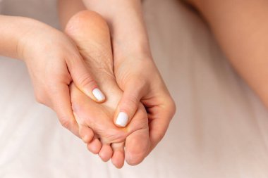 Kaplıca salonundaki genç bayana ayak masajı yapan masör elleri, sakinlik ve rahatlama atmosferi, vücut bakımı ve güzellik kavramı.