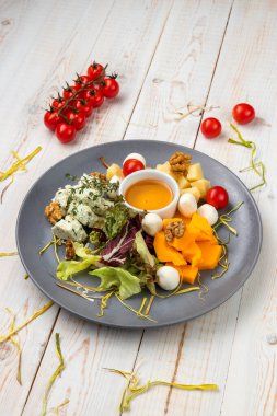 Karpuzlu, cevizli, otlu, sarı soslu ve peynirli yemek tabağı. Beyaz ahşap arka planda kırsal tarzda yemek restoranının menüsü.