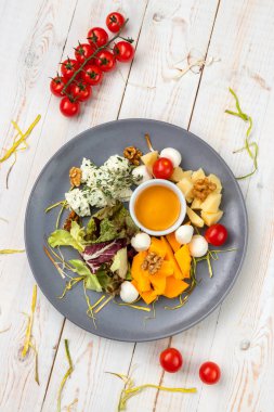 Karpuzlu, cevizli, otlu, sarı soslu ve peynirli yemek tabağı. Beyaz ahşap arka planda kırsal tarzda yemek restoranının menüsü.