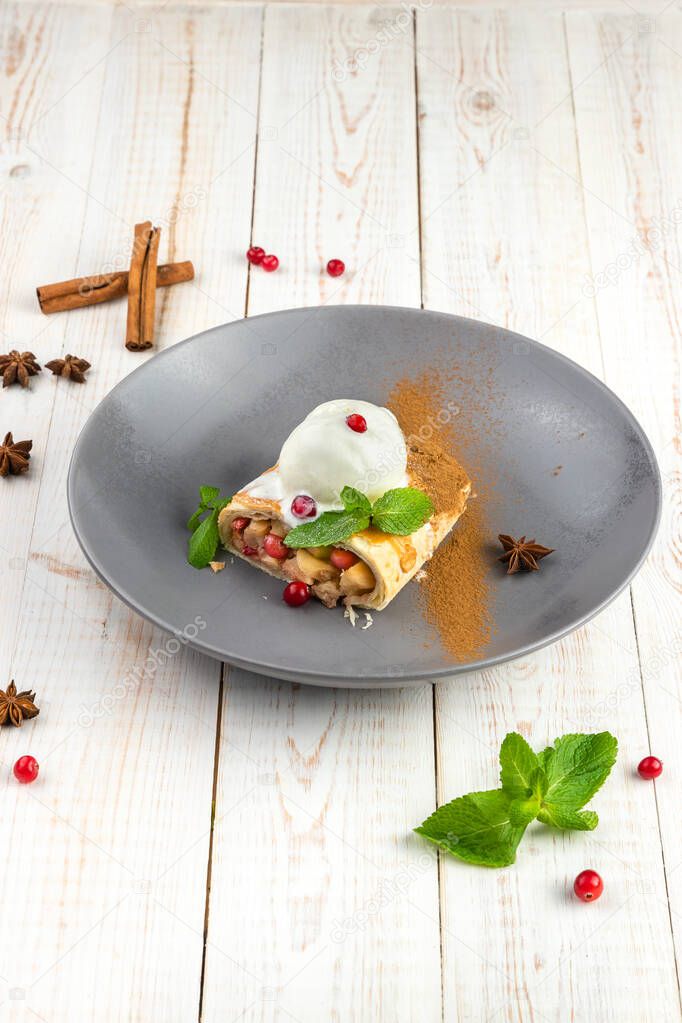 Apple and cranberry strudel on plate. Background with delicious dessert of russian cuisine. Lunch menu of food restaurant on white wooden table in rustic style, side view