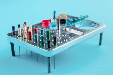 Metal bir stantta kanal tedavisi için kullanılan diş iğneleri seti. Mavi tıbbi altyapıda insan dişleri ve sağlık konsepti