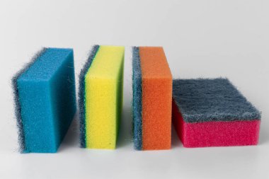 Beyaz arka planda izole edilmiş bulaşık yıkamak için yakın plan kırmızı, sarı, mavi ve turuncu süngerler