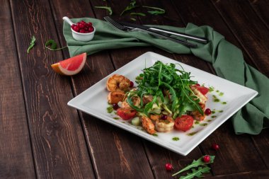 Sağlıklı kral karides yaz salatası domatesli, roka ve greyfurt bir restoranda ahşap masada, yan manzaralı.