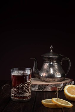 Kalıpları ve tabloları olan klasik demir çaydanlık ve ahşap masa üzerindeki bardak tutacağında limon olan bir bardak çay, fotokopi alanı olan restoran menüsü kavramı.