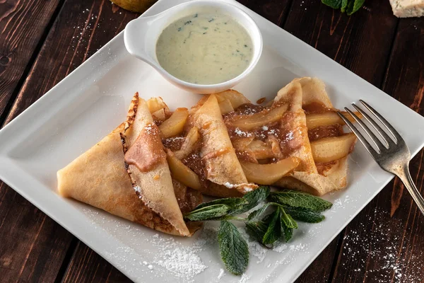 Yakın plan lezzetli ve armut ve peynirle doldurulmuş taze krepler, kırsal tarzda restoranda servis edilen ahşap masa, Rus festivali yemeği maslenitsa veya shrovetide konsepti