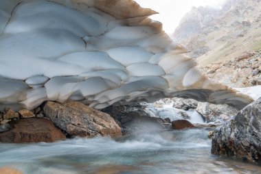 The beautiful view of frozen glacier and Kaznok river neat to Zmeya peak in Fann mountains in Tajikistan clipart