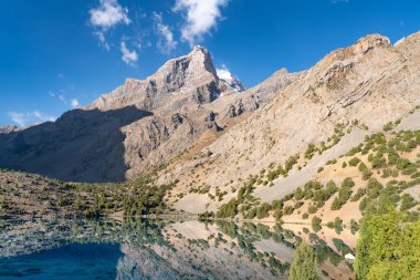 Temiz mavi gökyüzü, kayalık tepeler ve Tacikistan 'daki Fann Dağları' ndaki Alaudin Gölü manzaralı güzel dağ yürüyüşü yolu.