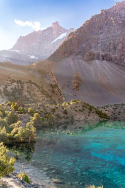 Temiz mavi gökyüzü, kayalık tepeler ve Tacikistan 'daki Fann Dağları' ndaki Alaudin Gölü manzaralı güzel dağ yürüyüşü yolu.