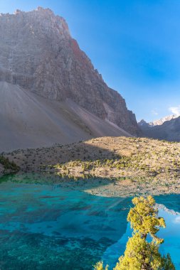 Temiz mavi gökyüzü, kayalık tepeler ve Tacikistan 'daki Fann Dağları' ndaki Alaudin Gölü manzaralı güzel dağ yürüyüşü yolu.