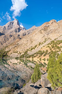 Temiz mavi gökyüzü, kayalık tepeler ve Tacikistan 'daki Fann Dağları' ndaki Alaudin Gölü manzaralı güzel dağ yürüyüşü yolu.