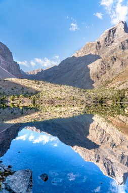 Temiz mavi gökyüzü, kayalık tepeler ve Tacikistan 'daki Fann Dağları' ndaki Alaudin Gölü manzaralı güzel dağ yürüyüşü yolu.