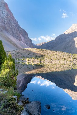 Temiz mavi gökyüzü, kayalık tepeler ve Tacikistan 'daki Fann Dağları' ndaki Alaudin Gölü manzaralı güzel dağ yürüyüşü yolu.