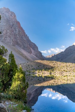 Temiz mavi gökyüzü, kayalık tepeler ve Tacikistan 'daki Fann Dağları' ndaki Alaudin Gölü manzaralı güzel dağ yürüyüşü yolu.