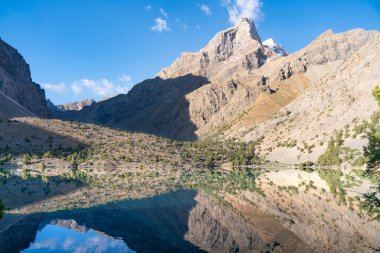 Temiz mavi gökyüzü, kayalık tepeler ve Tacikistan 'daki Fann Dağları' ndaki Alaudin Gölü manzaralı güzel dağ yürüyüşü yolu.