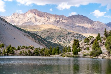 Temiz mavi gökyüzü, kayalık tepeler ve Tacikistan 'daki Fann Dağları' ndaki Alaudin Gölü manzaralı güzel dağ yürüyüşü yolu.