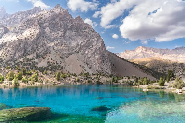 Temiz mavi gökyüzü, kayalık tepeler ve Tacikistan 'daki Fann Dağları' ndaki Alaudin Gölü manzaralı güzel dağ yürüyüşü yolu.