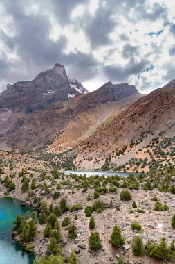 Temiz mavi gökyüzü, kayalık tepeler ve Tacikistan 'daki Fann Dağları' ndaki Alaudin Gölü manzaralı güzel dağ yürüyüşü yolu.