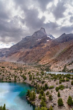 Temiz mavi gökyüzü, kayalık tepeler ve Tacikistan 'daki Fann Dağları' ndaki Alaudin Gölü manzaralı güzel dağ yürüyüşü yolu.