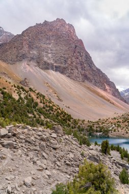 Temiz mavi gökyüzü, kayalık tepeler ve Tacikistan 'daki Fann Dağları' ndaki Alaudin Gölü manzaralı güzel dağ yürüyüşü yolu.