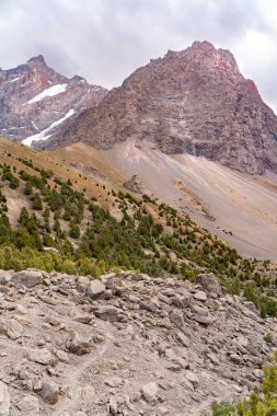 Temiz mavi gökyüzü, kayalık tepeler ve Tacikistan 'daki Fann Dağları' ndaki Alaudin Gölü manzaralı güzel dağ yürüyüşü yolu.