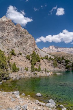 Temiz mavi gökyüzü, kayalık tepeler ve Tacikistan 'daki Fann Dağları' ndaki Alaudin Gölü manzaralı güzel dağ yürüyüşü yolu.