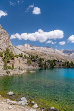 Temiz mavi gökyüzü, kayalık tepeler ve Tacikistan 'daki Fann Dağları' ndaki Alaudin Gölü manzaralı güzel dağ yürüyüşü yolu.