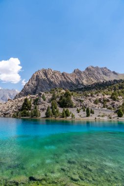 Temiz mavi gökyüzü, kayalık tepeler ve Tacikistan 'daki Fann Dağları' ndaki Alaudin Gölü manzaralı güzel dağ yürüyüşü yolu.