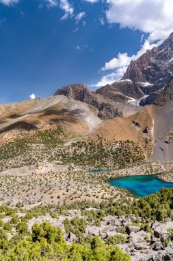 Temiz mavi gökyüzü, kayalık tepeler ve Tacikistan 'daki Fann Dağları' ndaki Alaudin Gölü manzaralı güzel dağ yürüyüşü yolu.