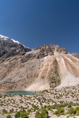 Temiz mavi gökyüzü, kayalık tepeler ve Tacikistan 'daki Fann dağlarında taze dağ gölü olan güzel dağ yürüyüşü yolu.