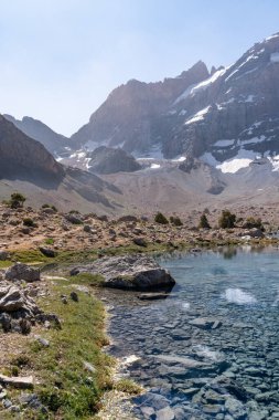 Temiz mavi gökyüzü, kayalık tepeler ve Tacikistan 'daki Fann dağlarında taze dağ gölü olan güzel dağ yürüyüşü yolu.