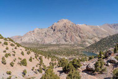 Temiz mavi gökyüzü, kayalık tepeler ve Tacikistan 'daki Fann dağlarındaki taze dağ deresi ile güzel dağ yürüyüşü yolu.