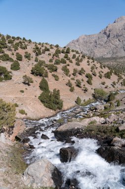 Temiz mavi gökyüzü, kayalık tepeler ve Tacikistan 'daki Fann dağlarındaki taze dağ deresi ile güzel dağ yürüyüşü yolu.