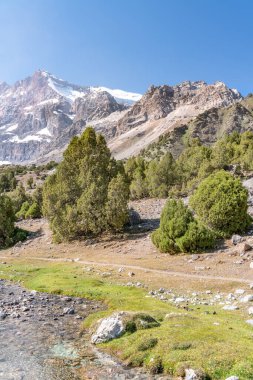 Temiz mavi gökyüzü, kayalık tepeler ve Tacikistan 'daki Fann dağlarındaki taze dağ deresi ile güzel dağ yürüyüşü yolu.