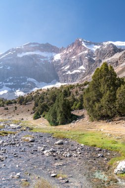 Temiz mavi gökyüzü, kayalık tepeler ve Tacikistan 'daki Fann dağlarındaki taze dağ deresi ile güzel dağ yürüyüşü yolu.