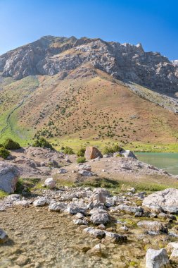 Pamir sıradağları manzarası ve Tacikistan 'daki Fann Dağları' ndaki Kulikalon Gölü 'ndeki huzurlu kamp alanı. Saf buz gölünün rengarenk yansıması.