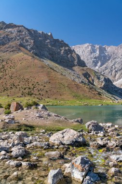 Pamir sıradağları manzarası ve Tacikistan 'daki Fann Dağları' ndaki Kulikalon Gölü 'ndeki huzurlu kamp alanı. Saf buz gölünün rengarenk yansıması.