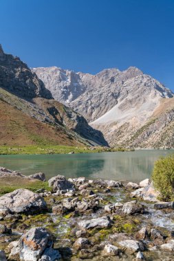 Pamir sıradağları manzarası ve Tacikistan 'daki Fann Dağları' ndaki Kulikalon Gölü 'ndeki huzurlu kamp alanı. Saf buz gölünün rengarenk yansıması.