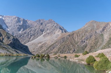 Pamir sıradağları manzarası ve Tacikistan 'daki Fann Dağları' ndaki Kulikalon Gölü 'ndeki huzurlu kamp alanı. Saf buz gölünün rengarenk yansıması.