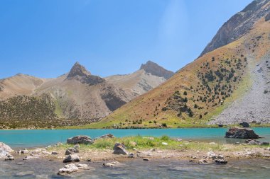 Pamir sıradağları manzarası ve Tacikistan 'daki Fann Dağları' ndaki Kulikalon Gölü 'ndeki huzurlu kamp alanı. Saf buz gölünün rengarenk yansıması.