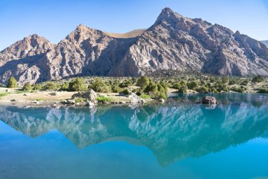 Pamir sıradağları manzarası ve Tacikistan 'daki Fann Dağları' ndaki Kulikalon Gölü 'ndeki huzurlu kamp alanı. Saf buz gölünün rengarenk yansıması.